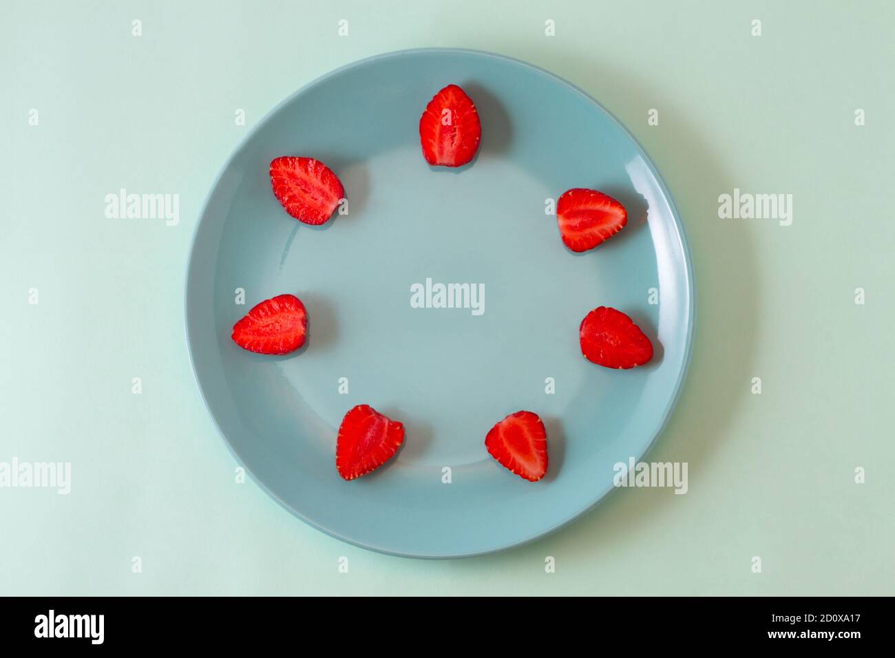 Helle Saftige Erdbeeren auf einem Pastell rosa Teller verteilen sich rund um die Kanten der Platte. Stockfoto