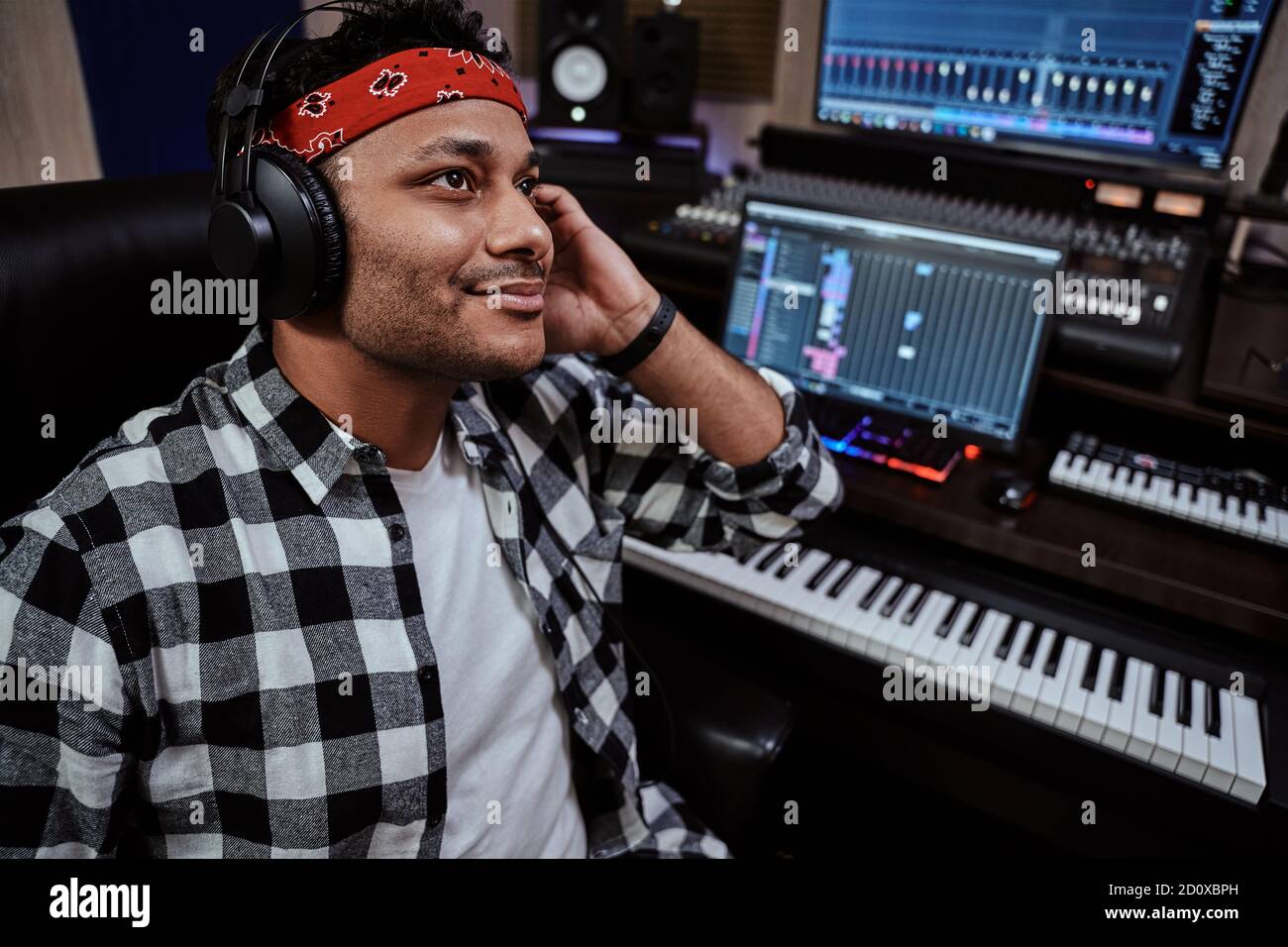 Junger Mann, männlicher Künstler in Kopfhörern lächelnd, während er Musik im Aufnahmestudio hört Stockfoto