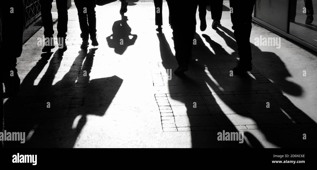 Verschwommene Schattensilhouette von Menschen, die auf einer Fußgängerstraße hereinlaufen Schwarz und Weiß mit hohem Kontrast Stockfoto