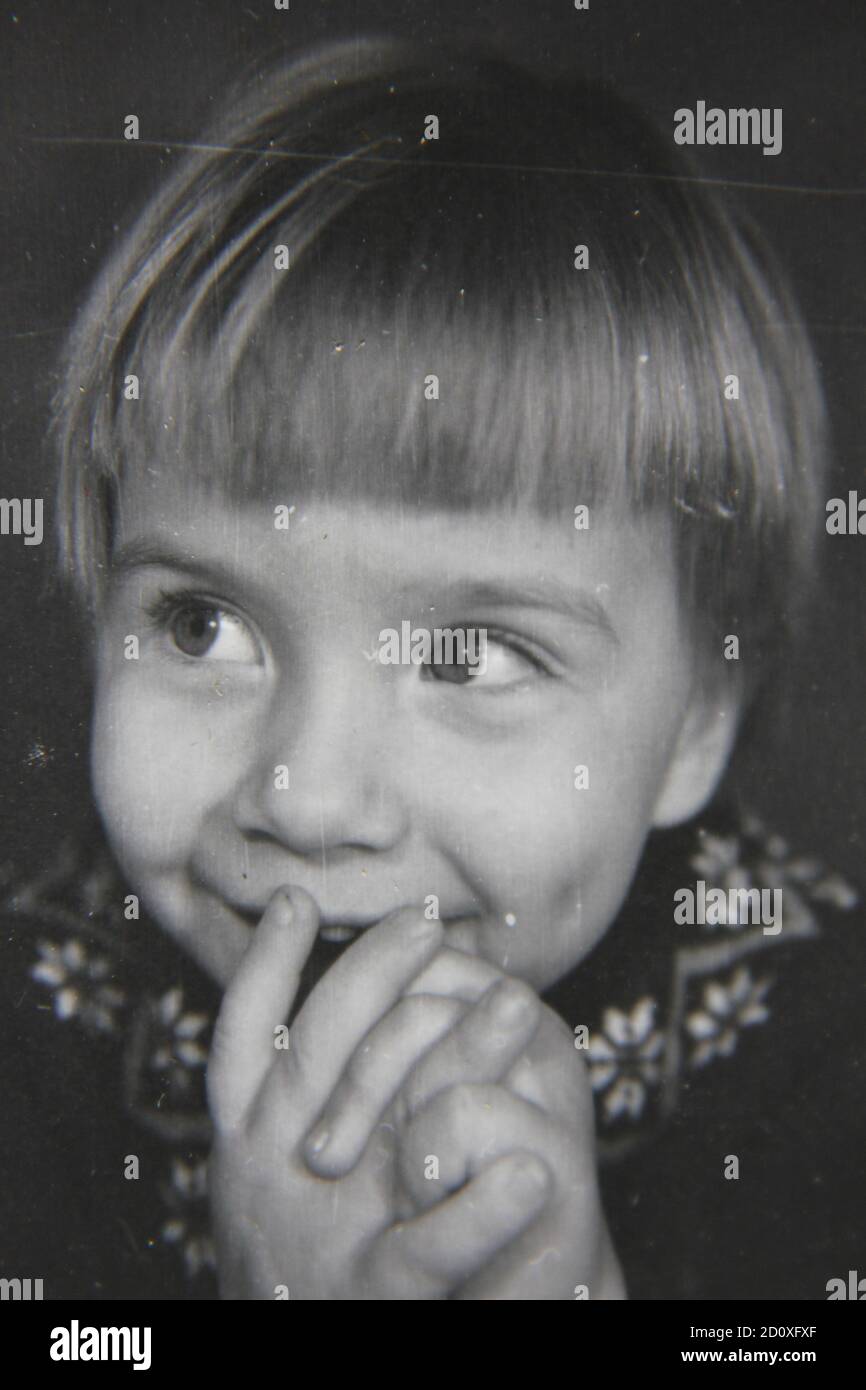 Feine 70er Jahre Vintage Schwarz-Weiß-Fotografie von einem frisch gesichtigen glücklichen kleinen Mädchen. Stockfoto