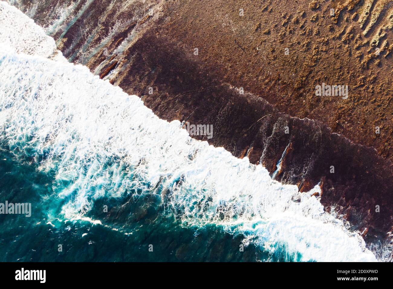 Majestätische arial Drohne Blick auf den dunklen tropischen Strand und brechende Wellen des Ozeans. Blauer Wasserhintergrund. Natur von Bali, Indonesien. Hohe Qualität Stockfoto