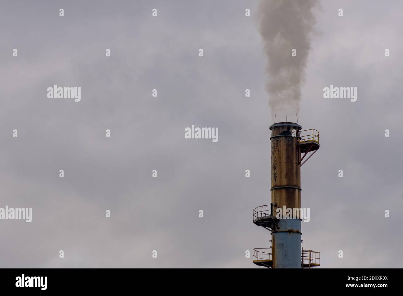 Ein industrieller Rauchschornstein weht einen Strom von Treibhausgasen in die Atmosphäre. Stockfoto