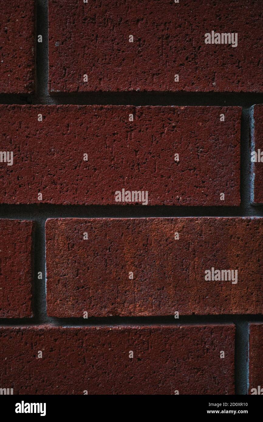 Ein Nahaufnahme-Bild im Hochformat mit roten Ziegelsteinen in einer Wand zeigt Textur und Details. Stockfoto