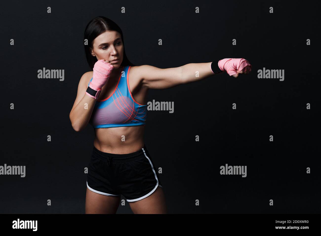 Sportsman muay thai Boxerin posiert im Trainingsstudio auf schwarzem Hintergrund. Stockfoto