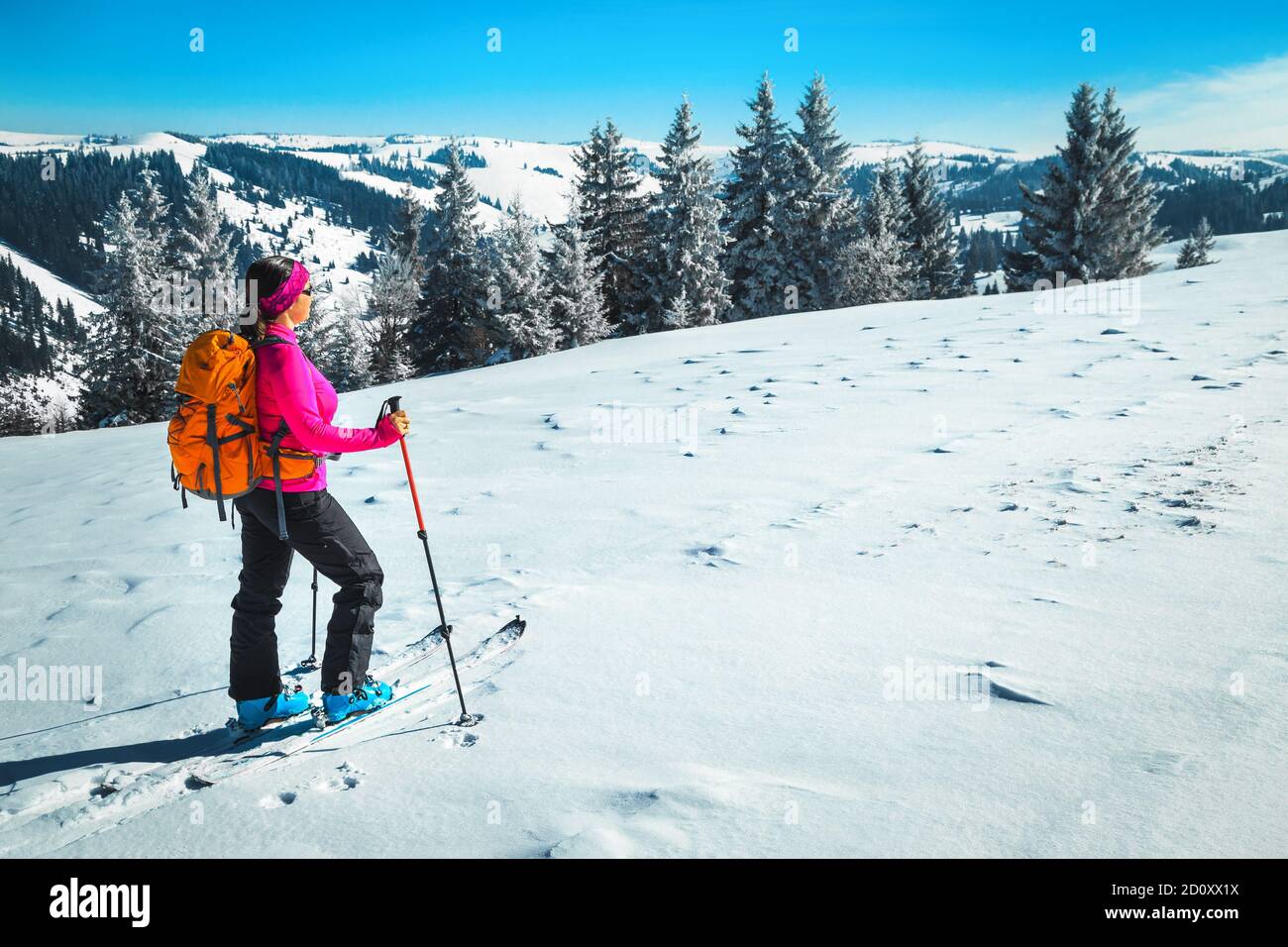 Skilanglauf auf den verschneiten Hügeln. Sportliche glückliche Frau mit buntem Rucksack, Skitouren im Pulverschnee und die Aussicht genießen, Karpaten, T Stockfoto