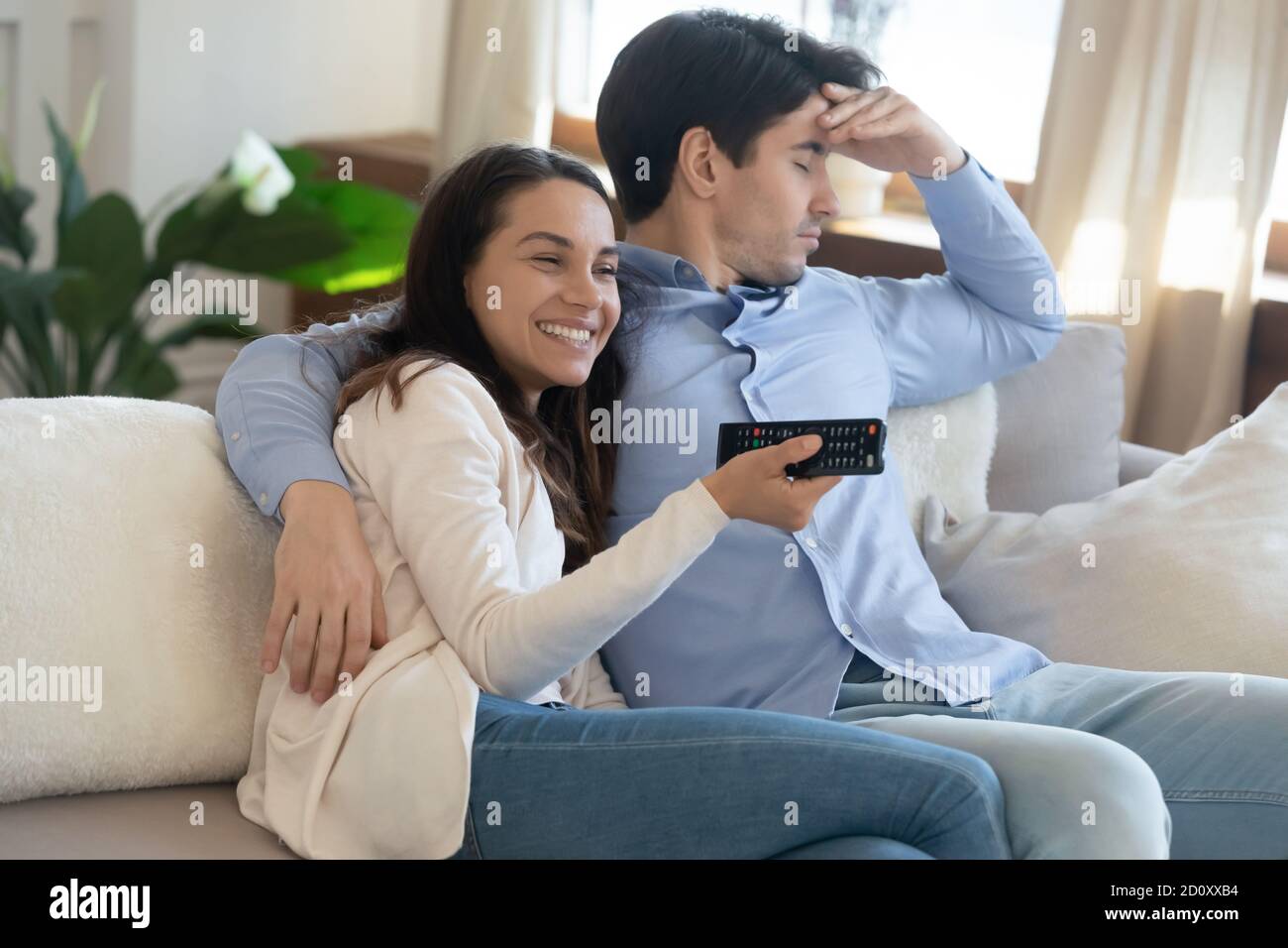 Junges Paar mit unterschiedlichen Interessen sehen zusammen fernsehen Stockfoto