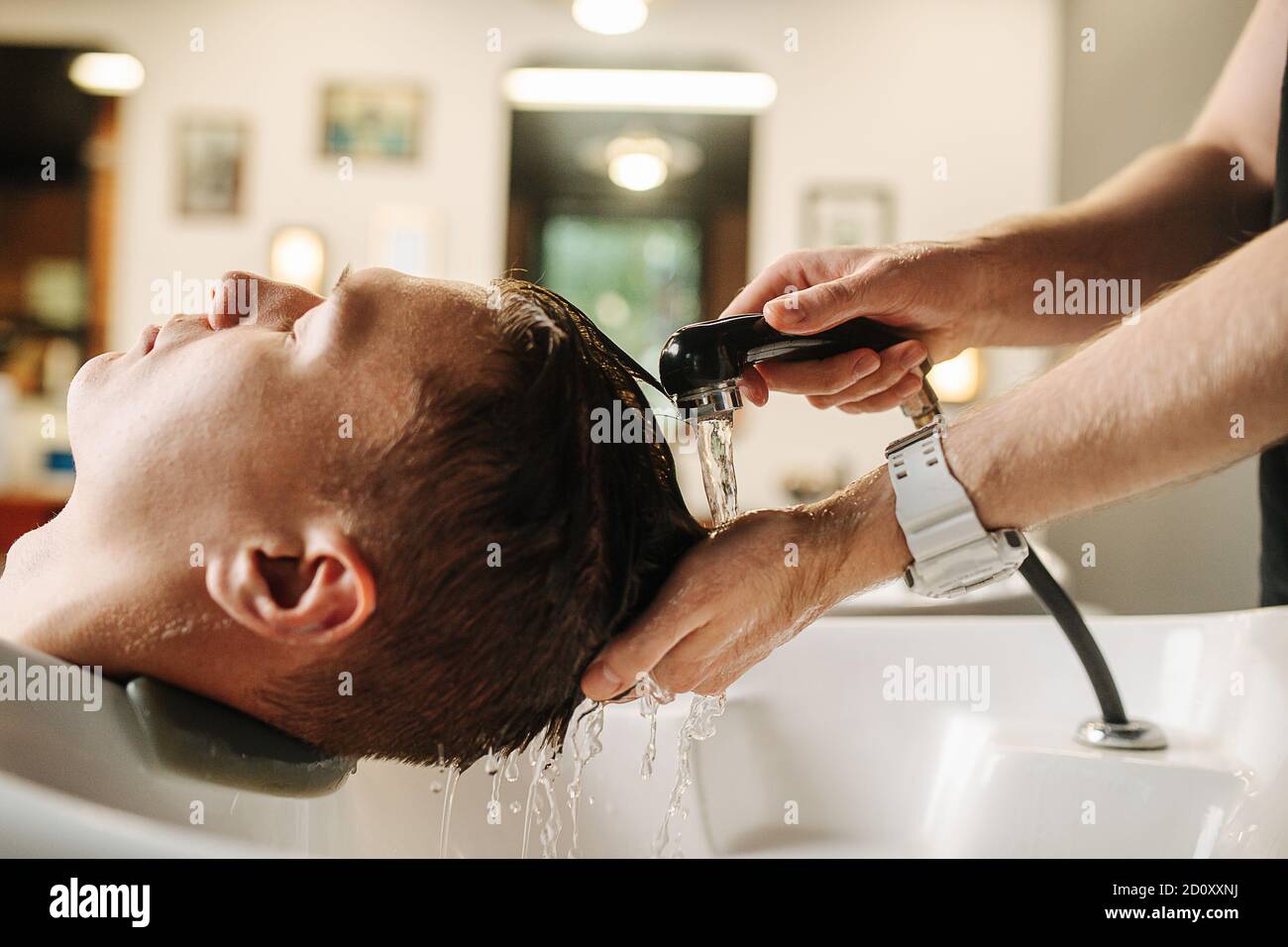 Friseur Hände waschen Client Kopf in einem spezialisierten Waschbecken in Ein Friseurladen Stockfoto