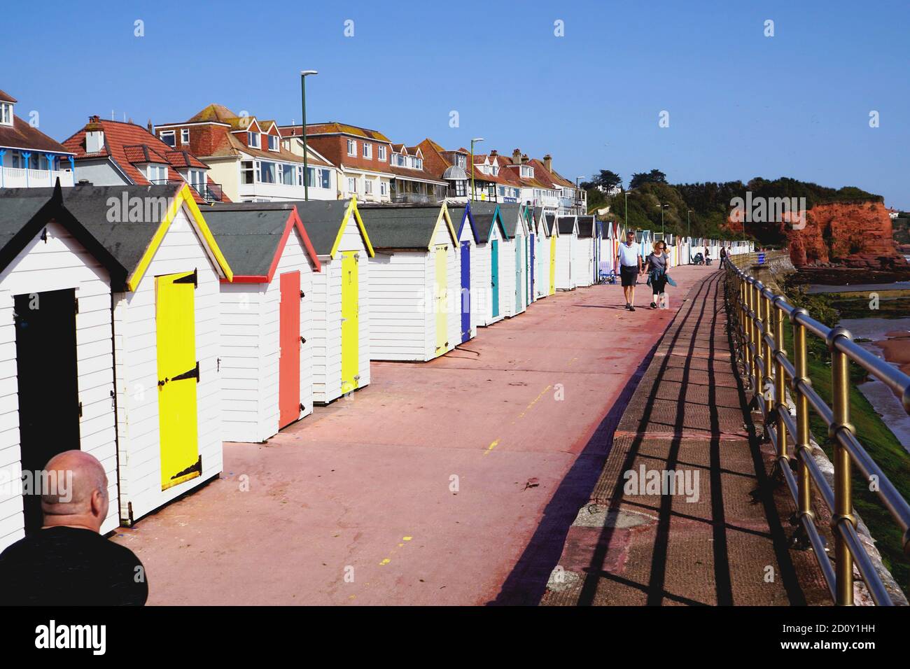 Paignton, Devon, Großbritannien. September 18, 2020. Urlauber, die auf der Promenade vor bunten Strandhütten am Preston Sands in Paignton in devon spazieren. Stockfoto