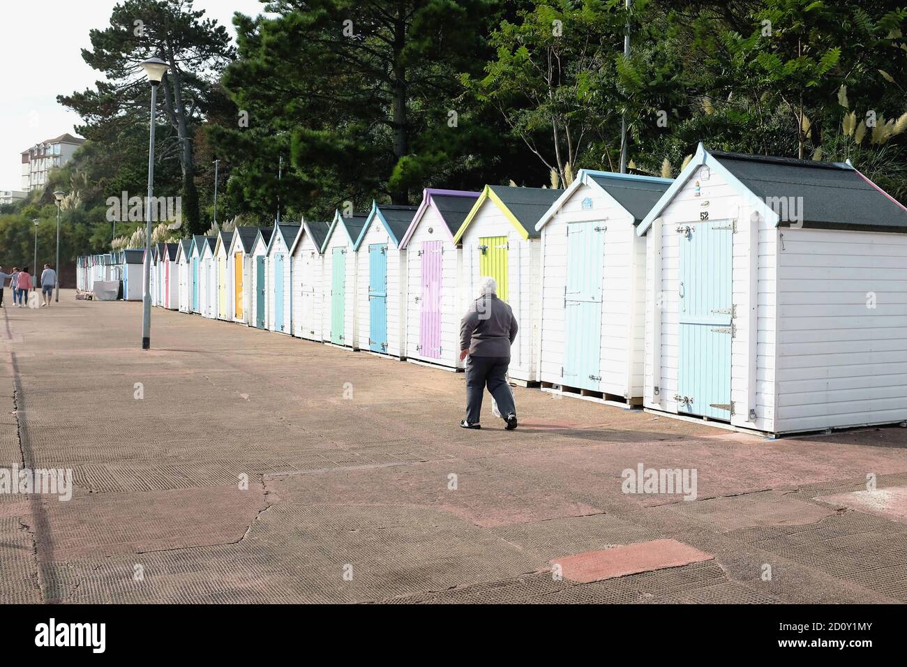 Goodrngton, Devon, Großbritannien. September 18, 2020. Urlauber, die auf der Promenade vor bunten Strandhütten in Goodrington bei Paignton in Devon, Großbritannien, spazieren gehen Stockfoto