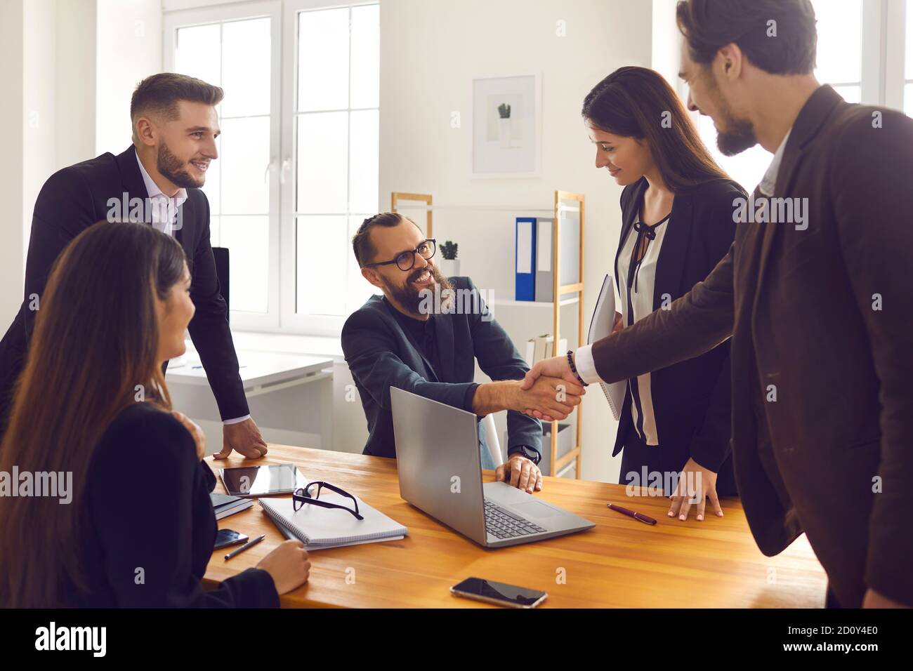 Lächelnde Geschäftspartner, die nach erfolgreichen Verhandlungen mit Kollegen die Hände schütteln Im Büro Stockfoto