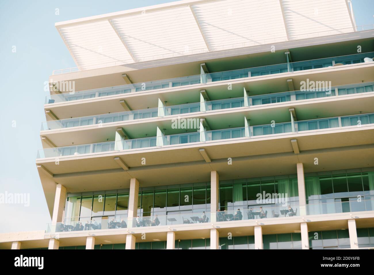 Ein hohes Gebäude mit einem weißen Baldachin und großen verglasten Balkonen. Stockfoto
