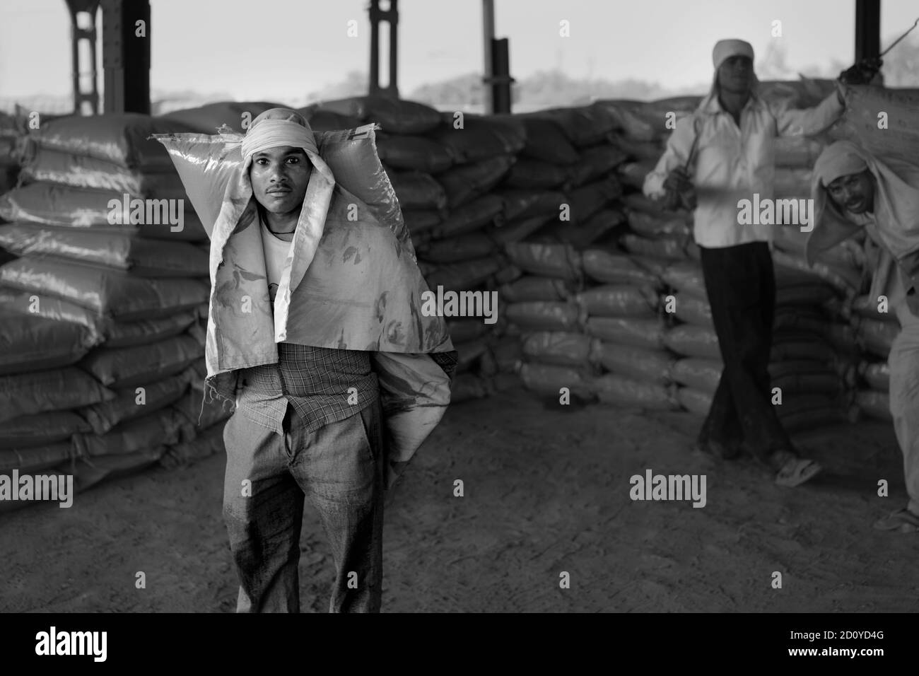 Man labors, um Zementbeutel unter staubigen Bedingungen aus dem Zug in heißen Sommerbedingungen in Mathura, Uttar Pradesh, Indien zu entladen. Stockfoto