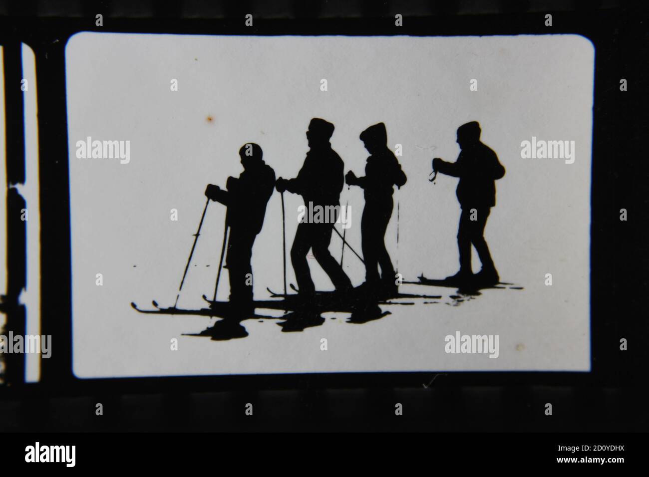Feine Schwarz-Weiß-Profilfotografie der 70er Jahre von Skifahrern auf der Skipiste in ihren kompletten Ski-Outfits und Skiern, die den Hügel hinunter fahren. Stockfoto