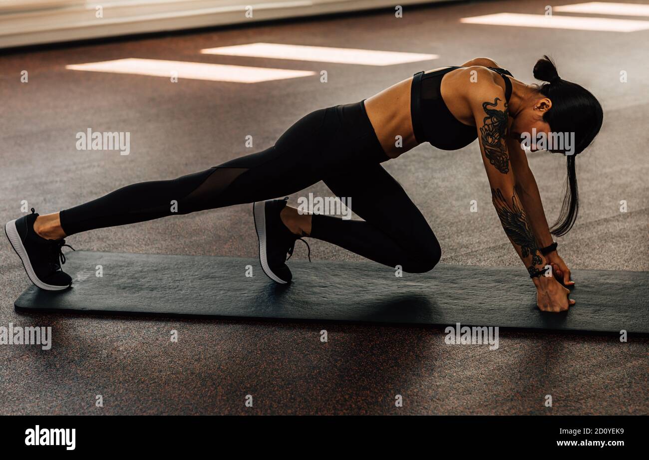Seitenansicht der schlanken Frau in Sportbekleidung Training auf Matte Und die Beine vor dem Training strecken Stockfoto