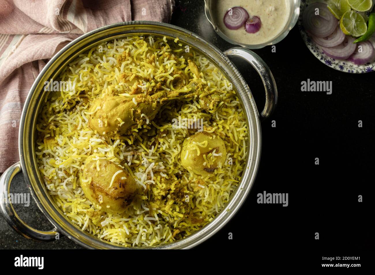Köstliche und würzige hausgemachte Huhn Biryani in traditionellen Schüssel Mit Raita und Salat auf schwarzem Hintergrund Stockfoto