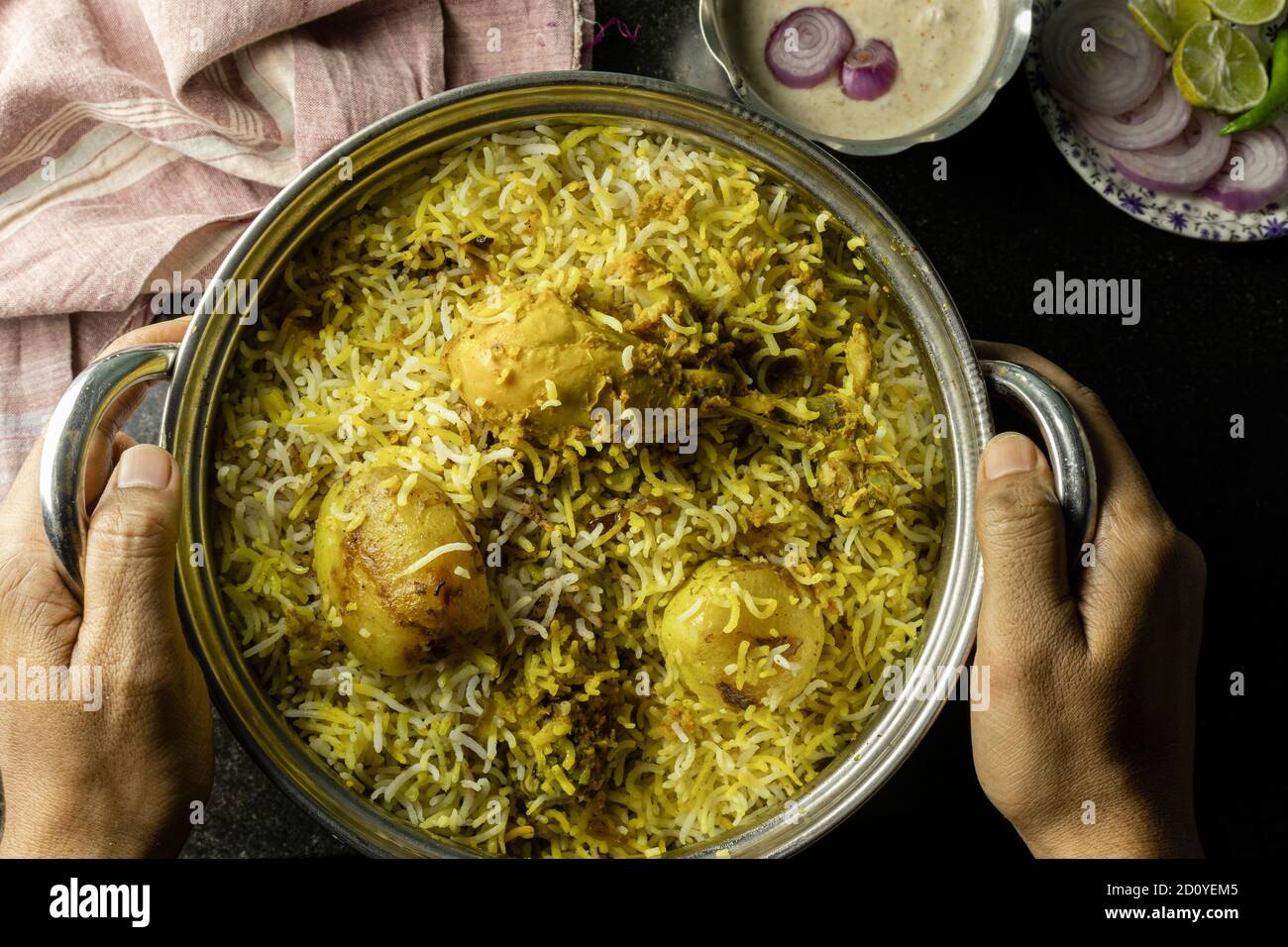 Köstliche und würzige hausgemachte Huhn Biryani in traditionellen Schüssel Mit Raita und Salat auf schwarzem Hintergrund Stockfoto