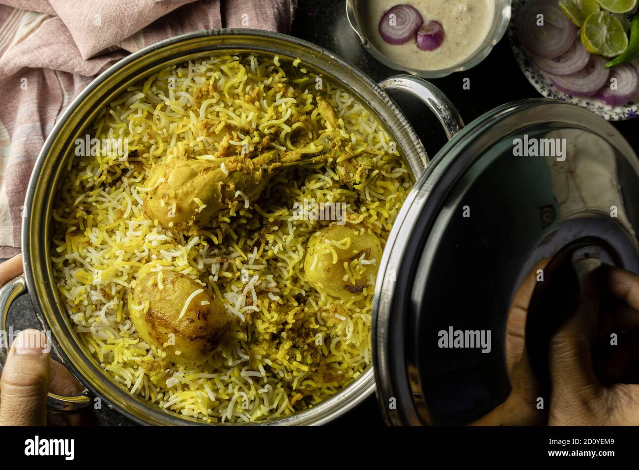 Köstliche und würzige hausgemachte Huhn Biryani in traditionellen Schüssel Mit Raita und Salat auf schwarzem Hintergrund Stockfoto
