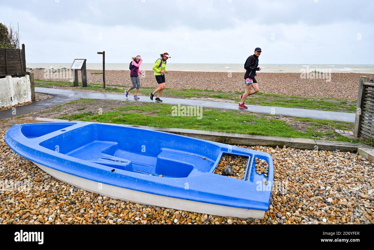 Worthing UK 4. Oktober 2020 - Läufer beim Virtual London Marathon kämpfen an einem nassen und windigen Tag an der Ferring-Küste bei Worthing gegen die Elemente, während sie ihre 20-Meilen-Marke erreichen : Credit Simon Dack / Alamy Live News Stockfoto