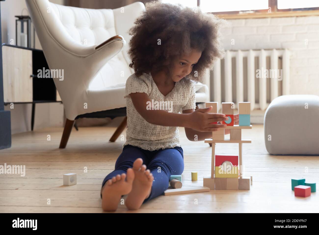 Fokussierte liebenswert kleine biracial Kind allein zu Hause spielen. Stockfoto