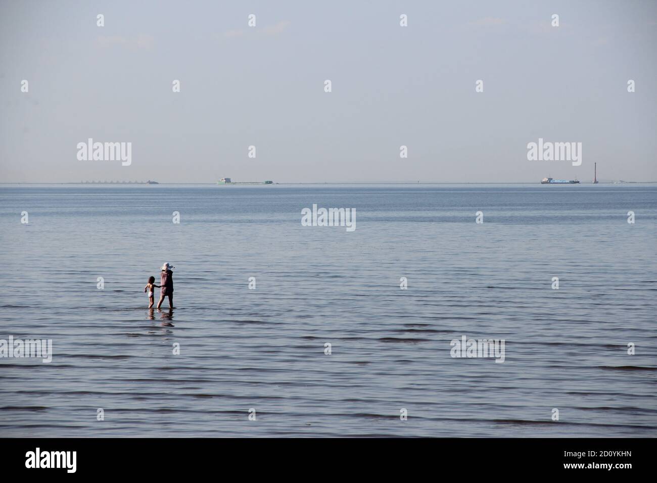 Menschen, die am Strand stehen und baden mit einem Unendliche Aussicht Stockfoto