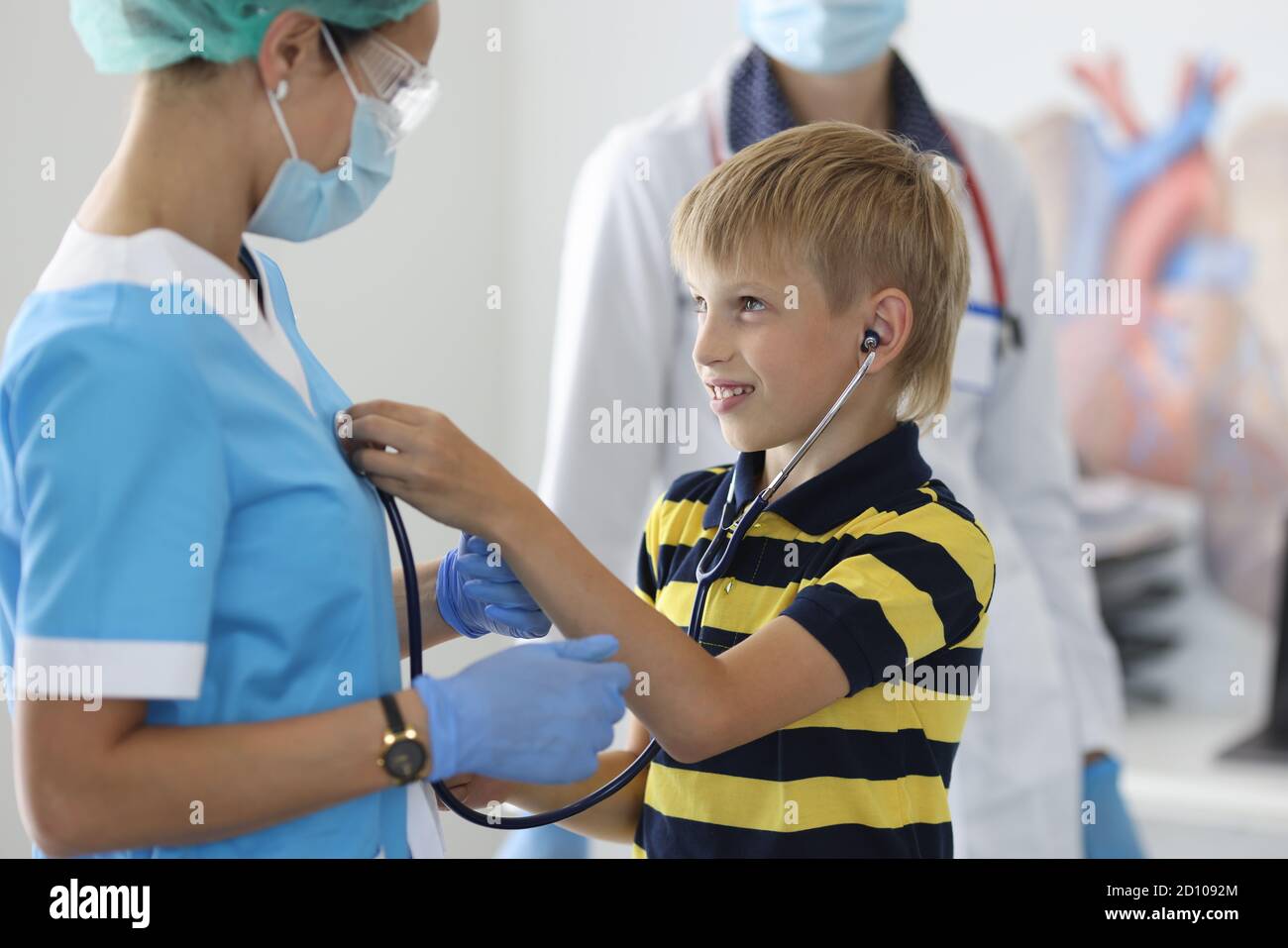 Junge im gestreiften T-Shirt mit schwarzem Stethoskop dem Herzschlag des Arztes zuhören. Stockfoto