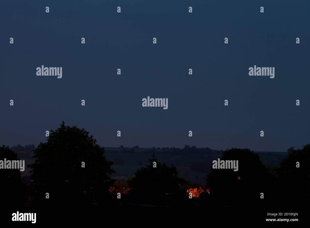 Natriumdampf Straßenbeleuchtung glitzert zwischen den fernen Bäumen in der Dämmerung. Stockfoto