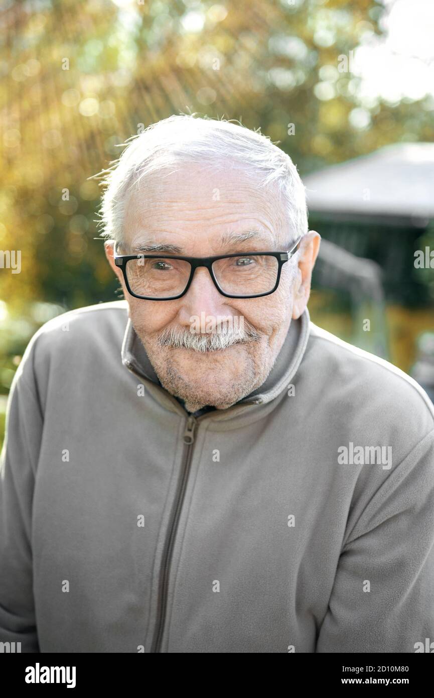 Fröhlicher grauhaariger alter Mann schaut auf den Gesprächspartner und  lächelt. Der alte Mann kann ohne Brille nicht sehr gut sehen. Porträt eines  fröhlichen alten Mannes Stockfotografie - Alamy