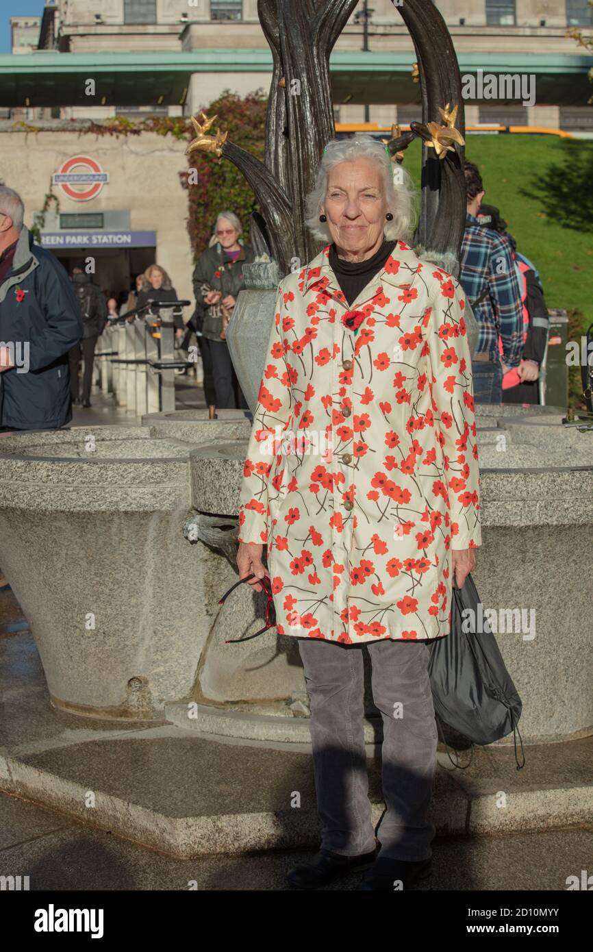 Senioren gesehen tragen einen Mantel mit Drucken von roten Mohnblumen in Erinnerung Sonntag 2018 in der Nähe des Eingangs der Green Park U-Bahn-Station. Stockfoto