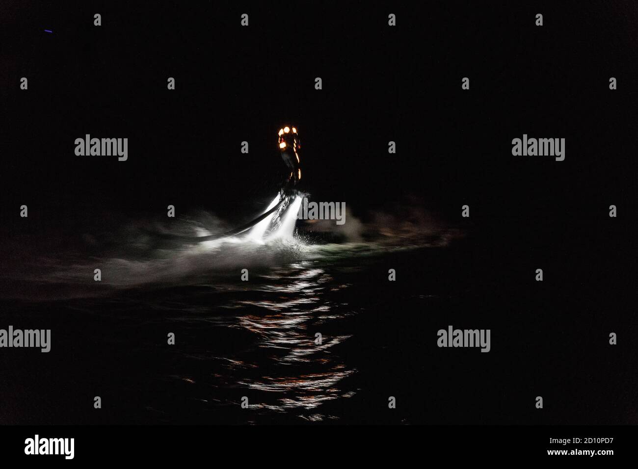 Flyboarding bei Nacht in einem Steinbruch in der Tschechischen Republik. Ein nicht identifizierter Mann führt nachts das Flyboarding durch. Bewegungseffekt, Langzeitbelichtung. Stockfoto