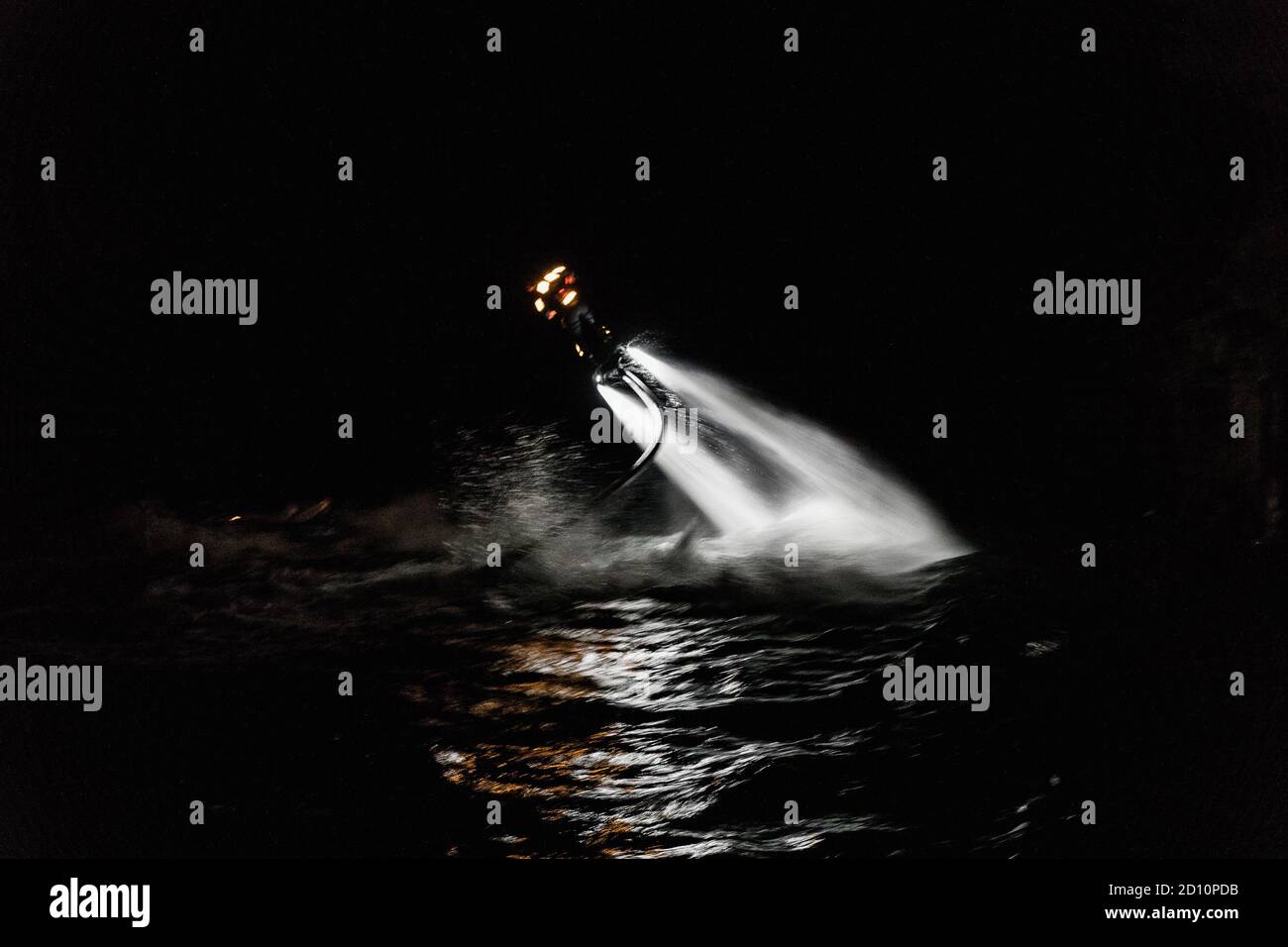 Flyboarding bei Nacht in einem Steinbruch in der Tschechischen Republik. Ein nicht identifizierter Mann führt nachts das Flyboarding durch. Bewegungseffekt, Langzeitbelichtung. Stockfoto