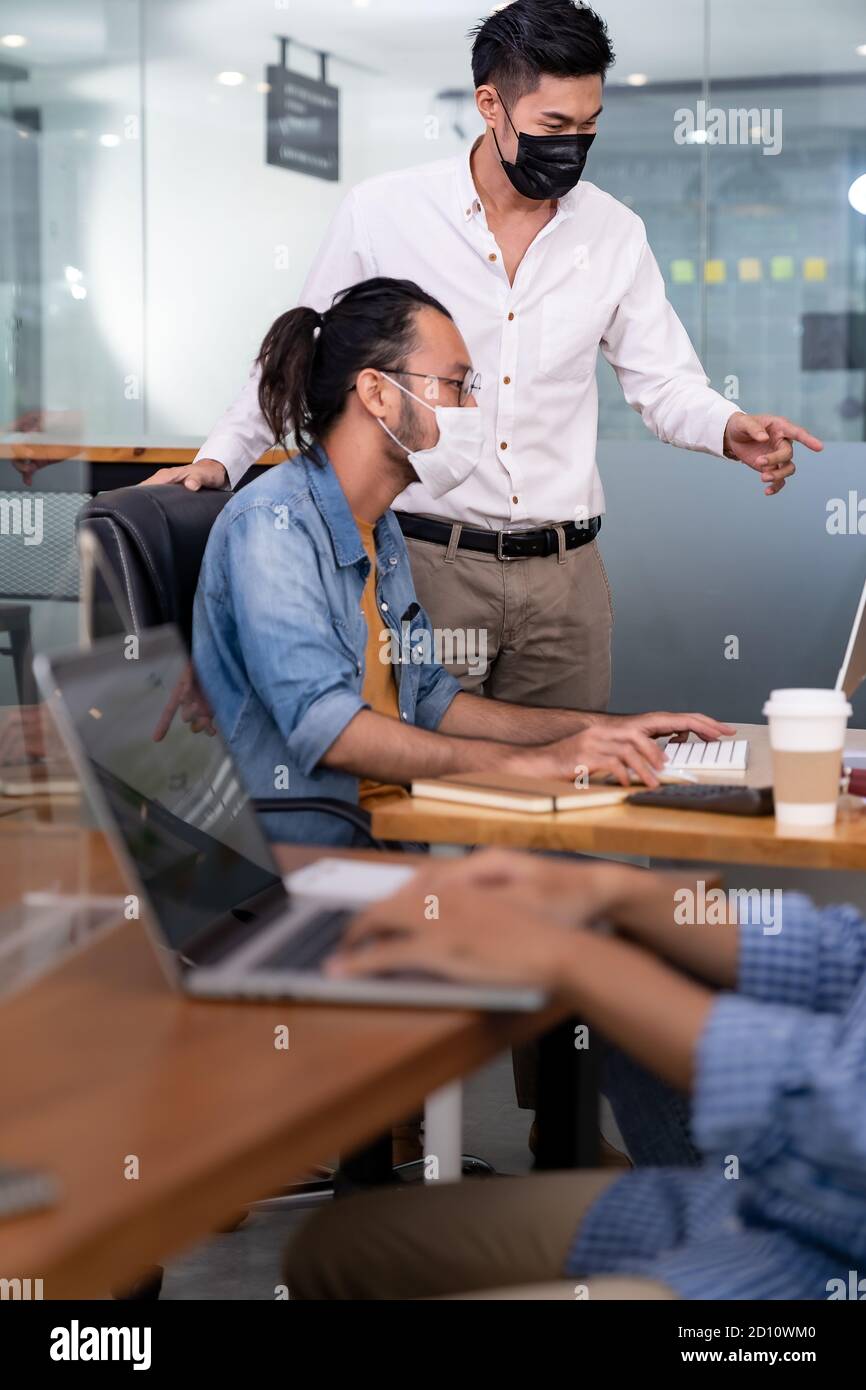 Gruppe von interracial Business Worker Team tragen schützende Gesichtsmaske in neuen normalen Büro mit sozialen Abstand Praxis mit Hand Desinfektionsmittel Alkohol Gel Stockfoto