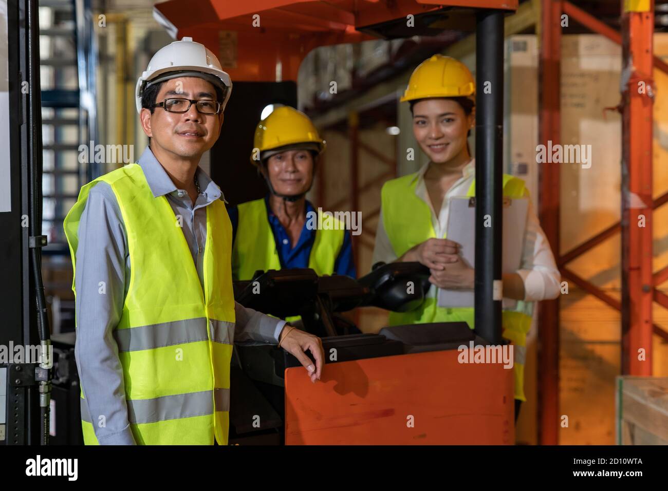 Portrait des asiatischen Lagermanagers und seines Teamarbeiters mit Gabelstapler im Hintergrund. Wiedereröffnung von Lagerbestandstechnologie und logis Stockfoto