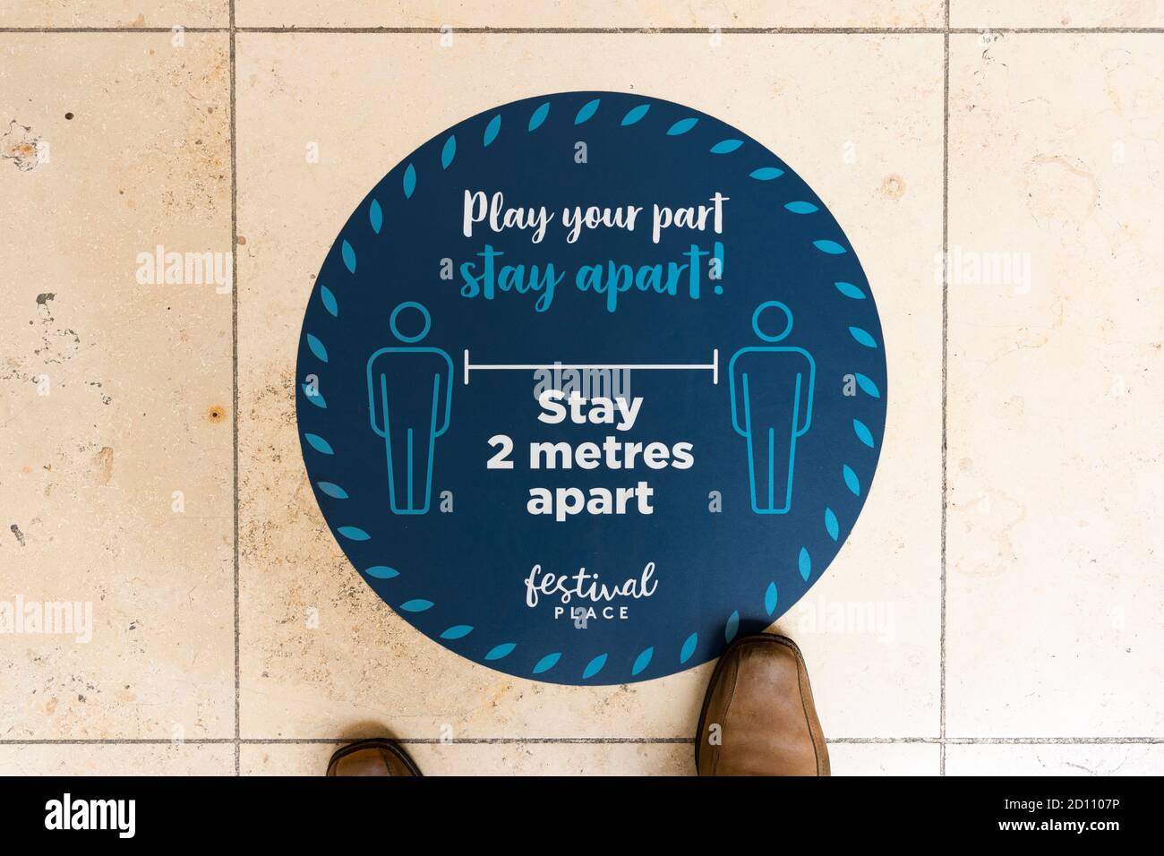 Ein Bodenaufkleber mit der Aufschrift "Play Your Part Stay Apart, Stay 2 Meter apart" für die soziale Distanz im Festival Place Einkaufszentrum während der Covid-19, Großbritannien Stockfoto