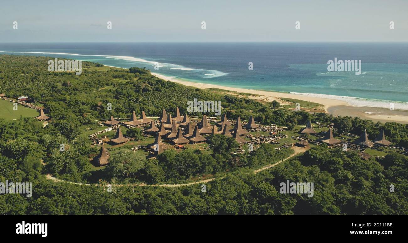 Aerial traditionellen Dorf mit verschnörkelten Dächern Häuser am Meer Sand Küste. Indonesische Touristenattraktion in grüner Landschaft an der Meeresbucht. Filmische Siedlung Wahrzeichen von Sumba Island, Asien Stockfoto