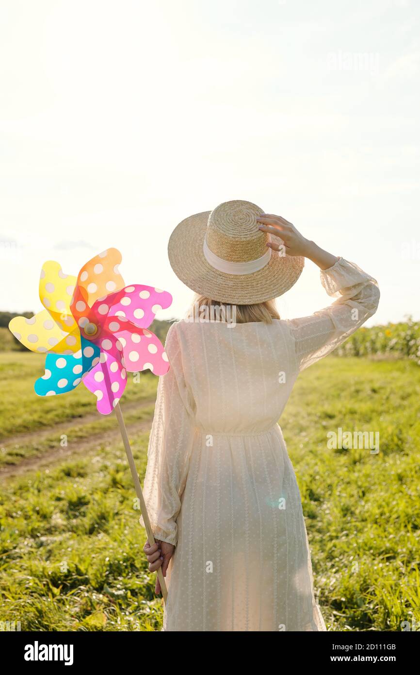 Rückansicht der jungen eleganten Frau in Hut und weiß Kleid genießen Sommertag Stockfoto
