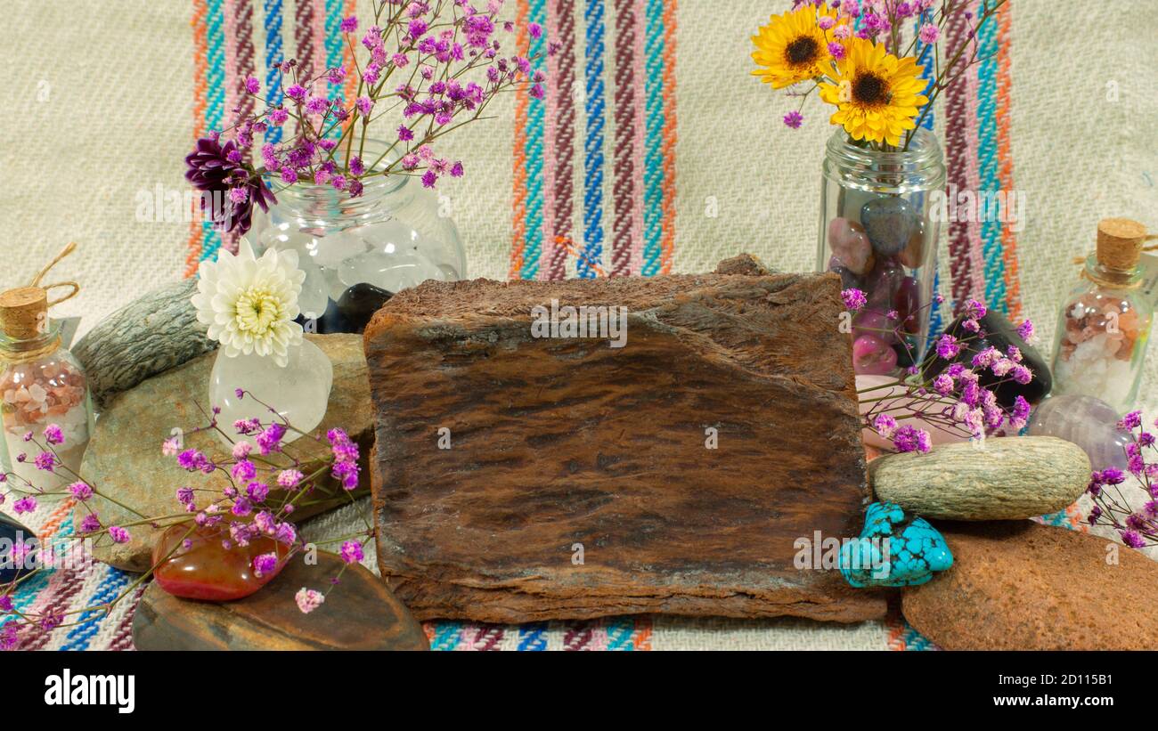 Komposition mit Holzstück, Steinen von gelben, weißen und violetten Farben und Blumen auf einem Hintergrund aus Stoff mit Linien Stockfoto