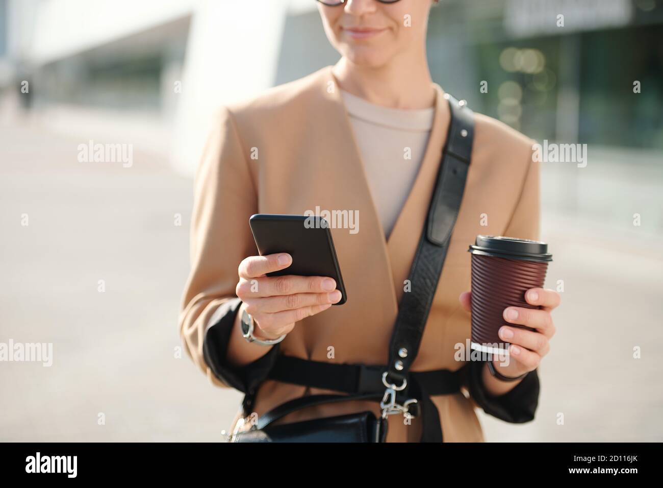 Hände der jungen Geschäftsfrau mit Glas Kaffee durchblättern Kontakte Stockfoto