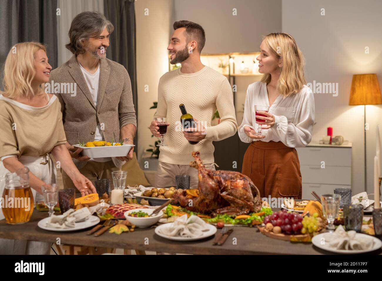 Glücklicher junger Mann mit Flasche und einem Glas Rotwein Betrachtet seine Eltern Stockfoto