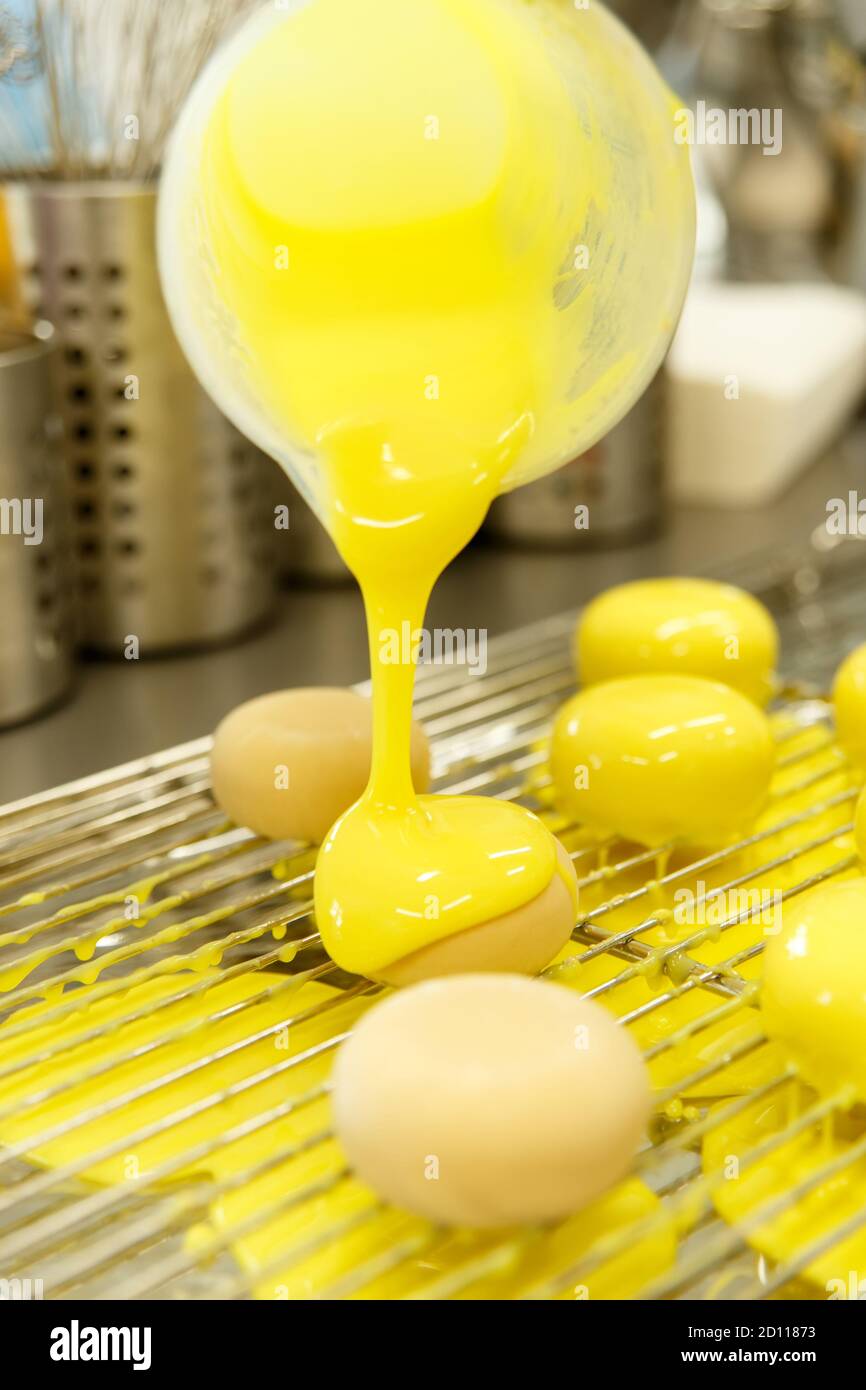 Der Konditor in der Küche glases Gebäck. Cook schmückt glasierte Backwaren mit einem dekorativen Element. Der Prozess des Kochens. Schritt für Schritt. Tutori Stockfoto