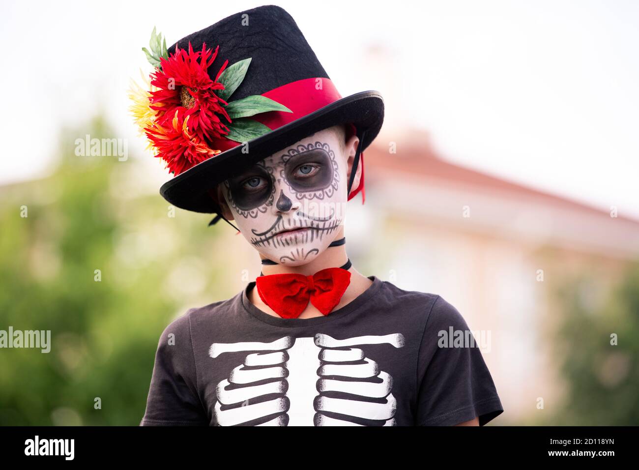 Gruseliger Junge mit bemaltem Gesicht im halloween Kostüm aus Skelett Mit eleganter Mütze Stockfoto