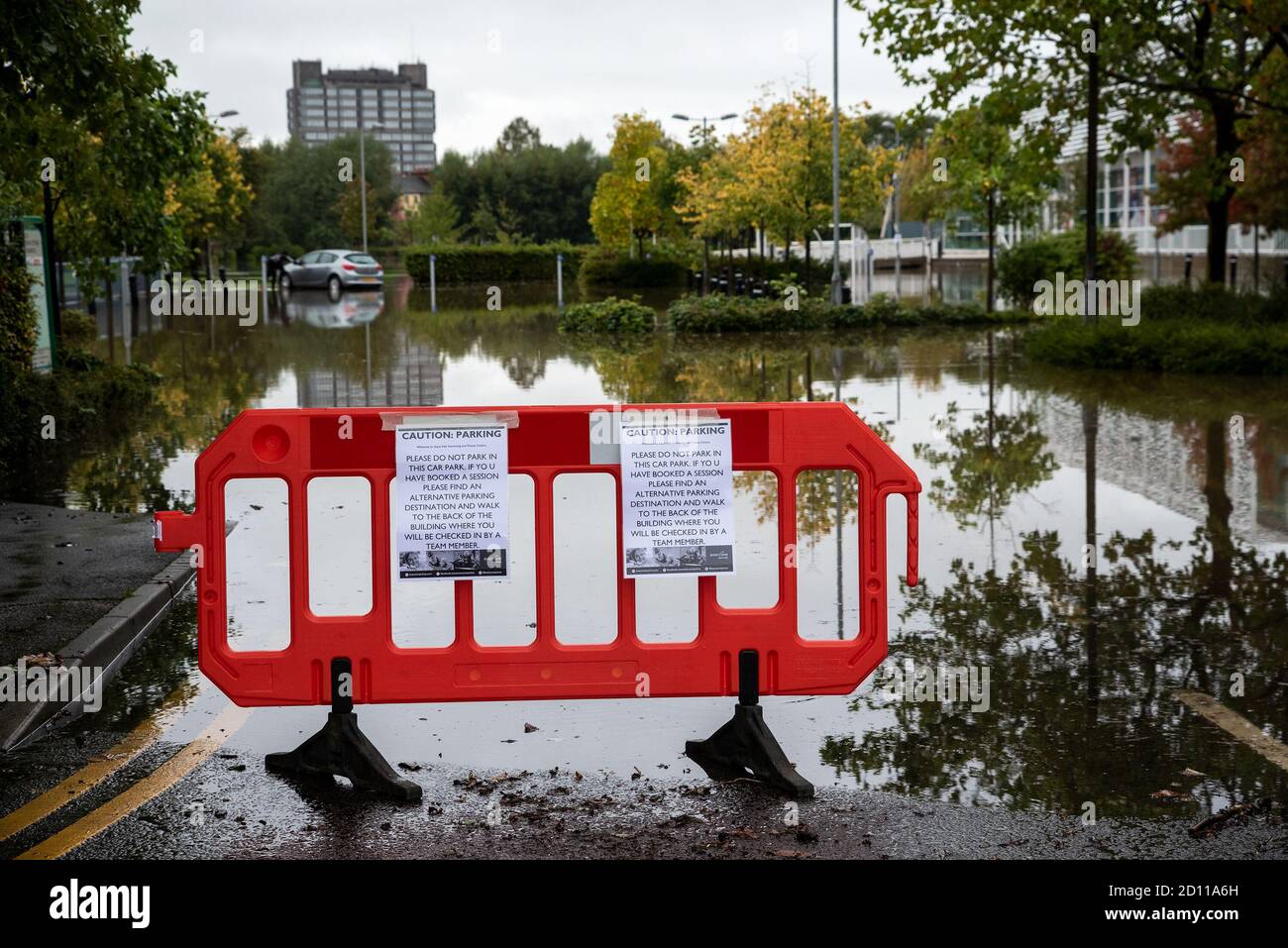 Aylesbury, Großbritannien. Oktober 2020. Sturm Alex Überschwemmungen in Aylesbury, Grafschaft Stadt Buckinghamshire. Ein Wochenende mit fast konstantem Starkregen veranlasste den Bear Brook, seine Ufer zu sprengen und den Vale Park und das Aqua Vale Swimming and Fitness Centre und seinen Parkplatz zu überfluten. Schranken und Schilder warnen potenzielle Nutzer des Parkplatzes, alternative Parkplätze zu finden. Die Schilder wurden hinzugefügt, während Autos auf dem überfluteten Parkplatz abgestellt wurden. Quelle: Stephen Bell/Alamy Stockfoto
