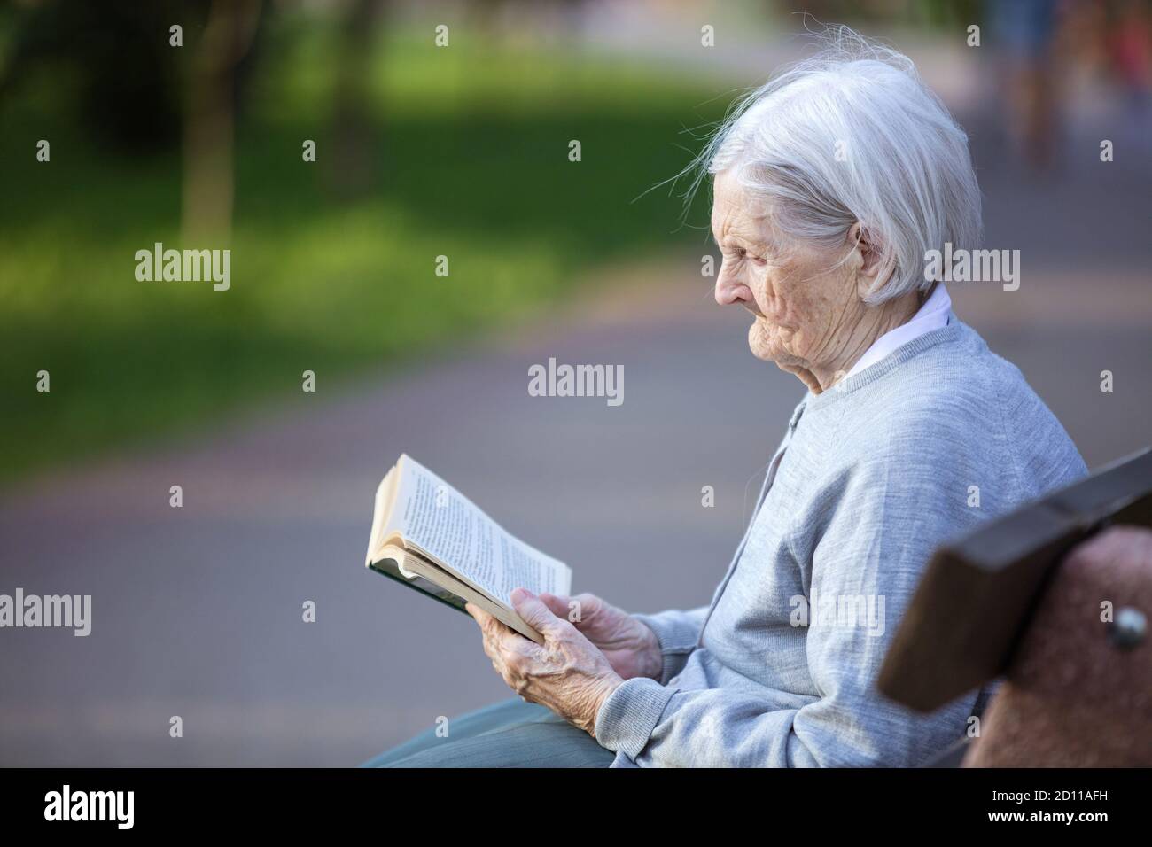 Porträt einer älteren Frau, die im Park ein Buch liest Stockfoto