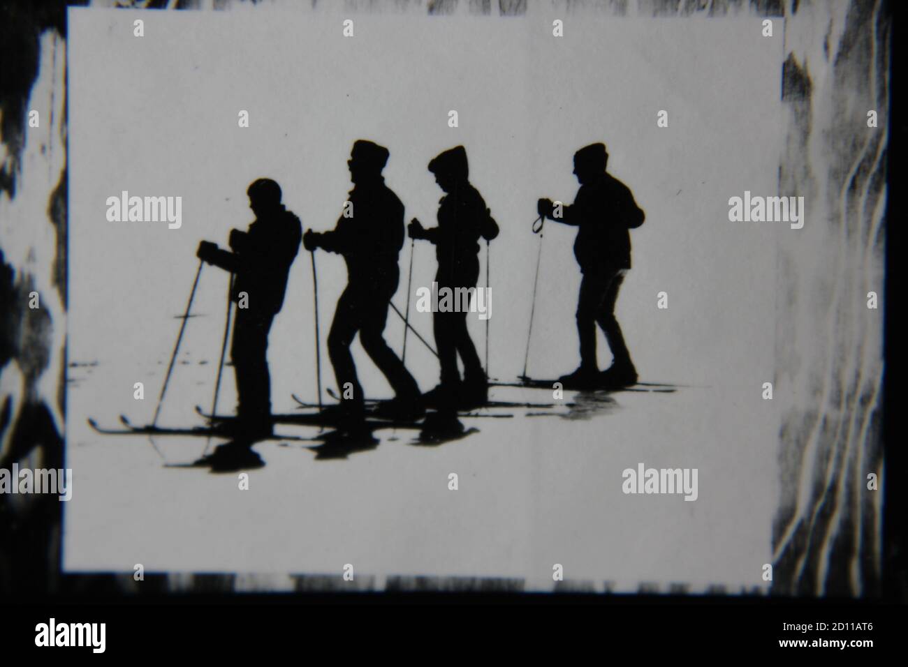 Feine Schwarz-Weiß-Profilfotografie der 70er Jahre von Skifahrern auf der Skipiste in ihren kompletten Ski-Outfits und Skiern, die den Hügel hinunter fahren. Stockfoto