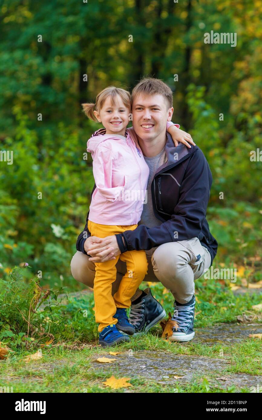 Ein Mädchen mit einem gebrochenen Arm umarmt ihren Vater Ein alter Park auf einem Herbstspaziergang Stockfoto