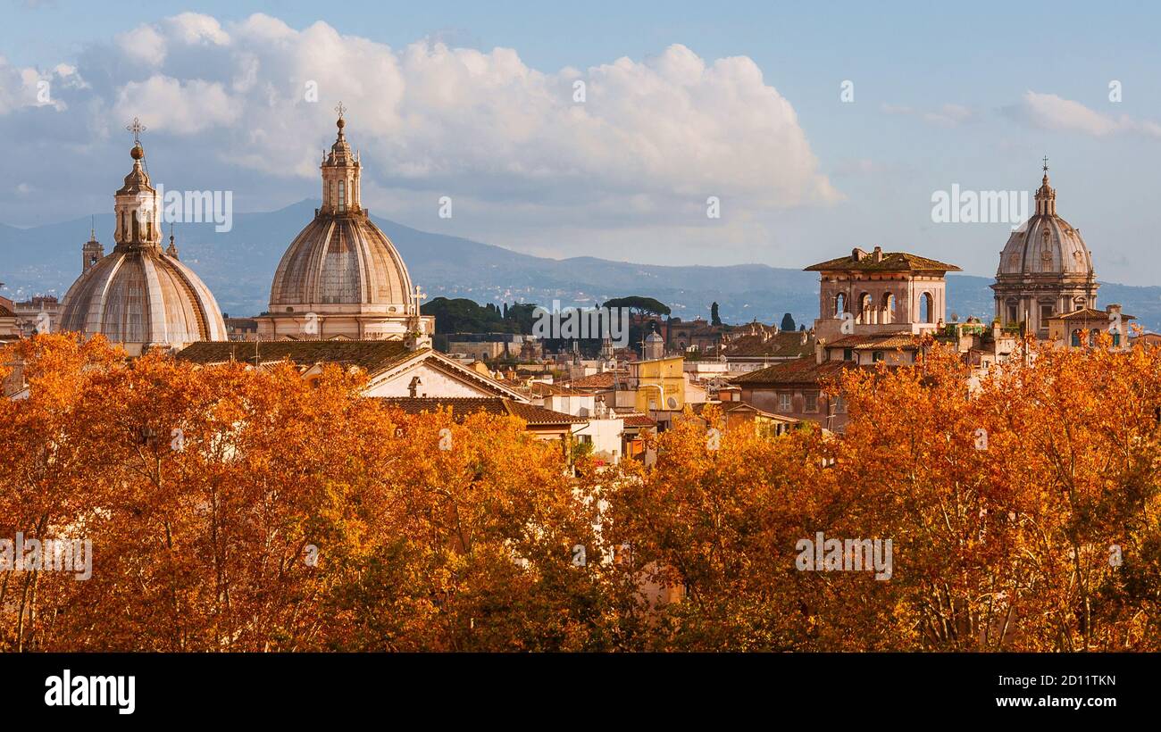 Skyline von Rom im Herbst. Barocke Kuppeln ragen über schöne rote und orangefarbene Blätter Stockfoto