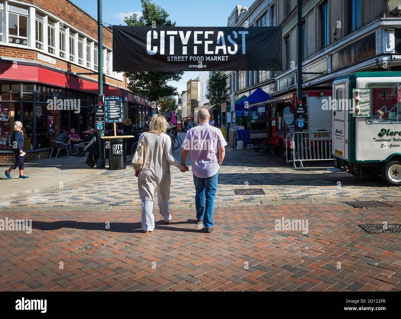 Mann und Frau halten die Hände in der Hand, um den Markt des Canterbury City Feast 2020 Street Food Festivals zu betreten. Stockfoto