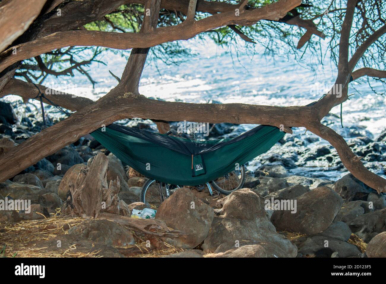 Maui, Hawaii. Ein Mann entspannt sich in einer Hängematte am Ufer des Pazifischen Ozeans, nachdem er die Nacht dort verbracht hat. Stockfoto