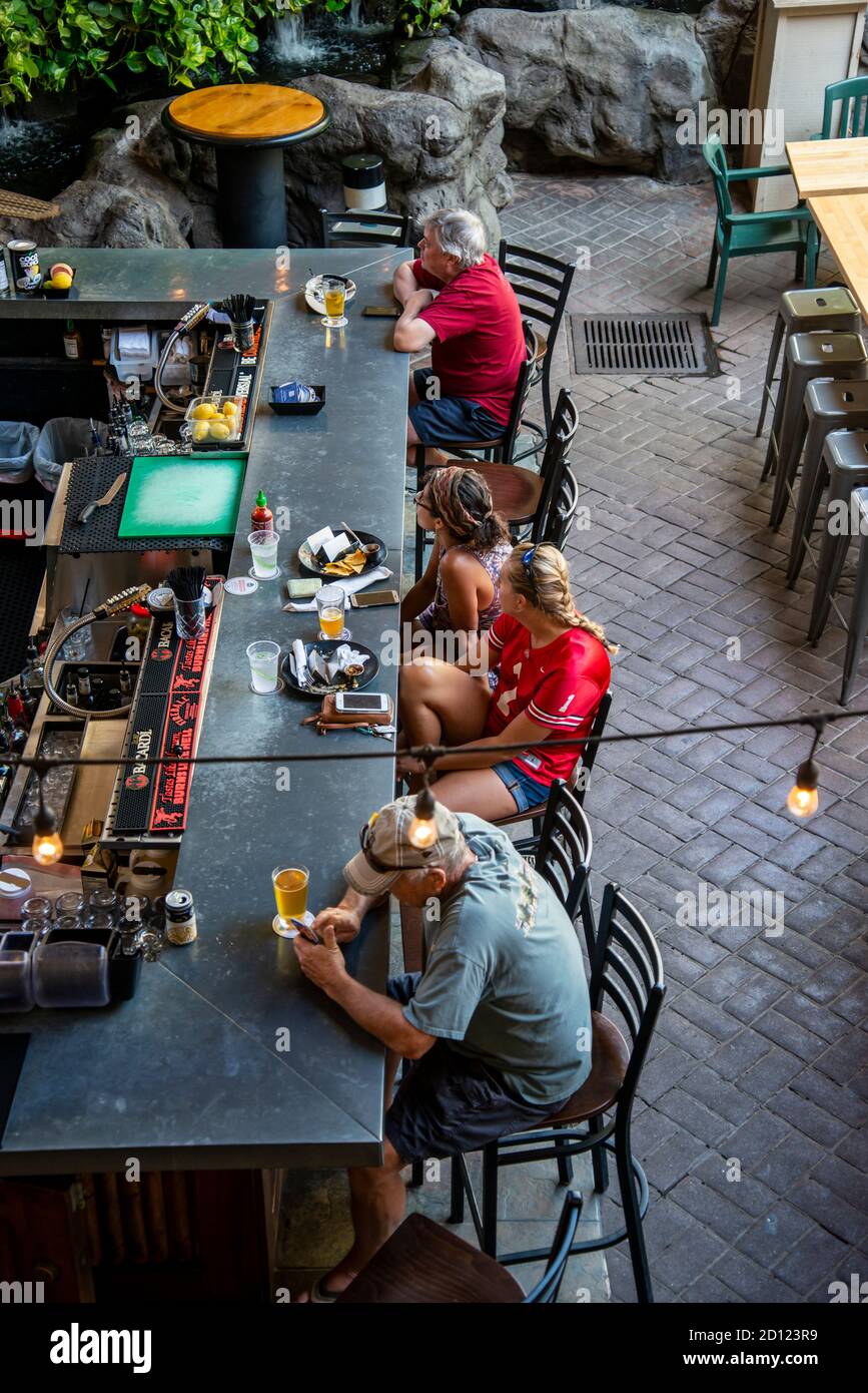 Maui, Hawaii. Barszene mit Leuten, die sich entspannen, ihr Telefon benutzen und Essen in Lahaina genießen. Stockfoto