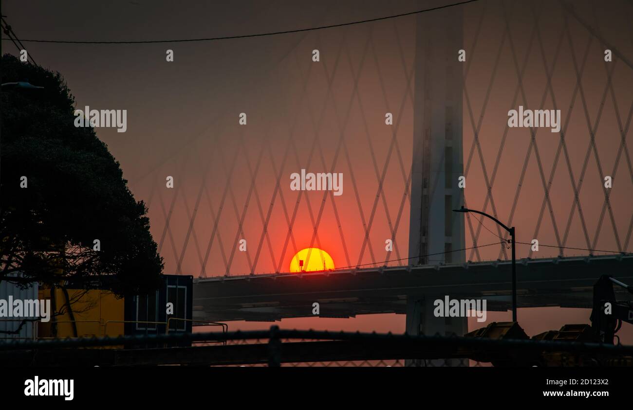 Aufgehende Sonne Feuerball über San Francisco Bay Brücke aus Waldbrände 2020 Stockfoto