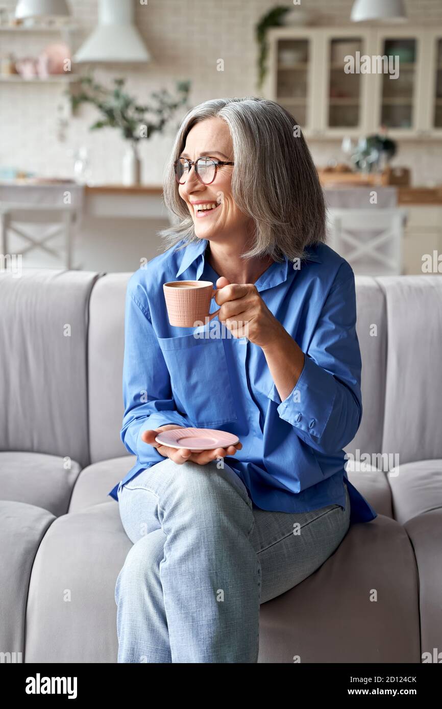 Glücklich entspannt ältere Frau trinken Kaffee entspannen auf dem Sofa zu Hause. Stockfoto